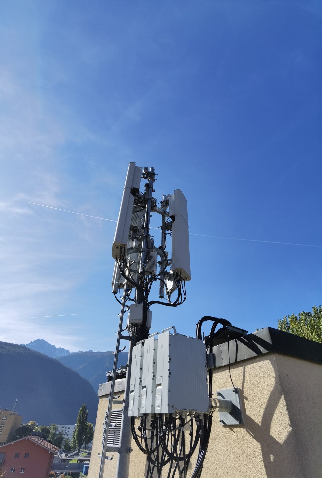A rooftop telecommunication mast under a blue sky.